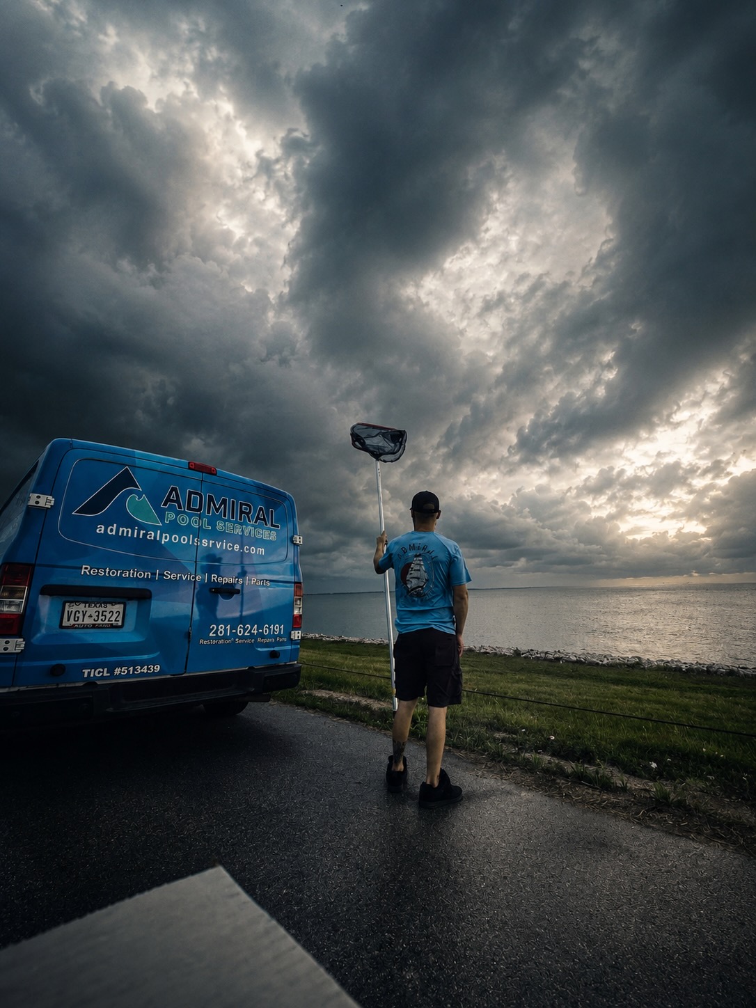 Admiral Pool Service technician with skimmer net beside Admiral service van along Galveston Bay coastline in Texas City, TX